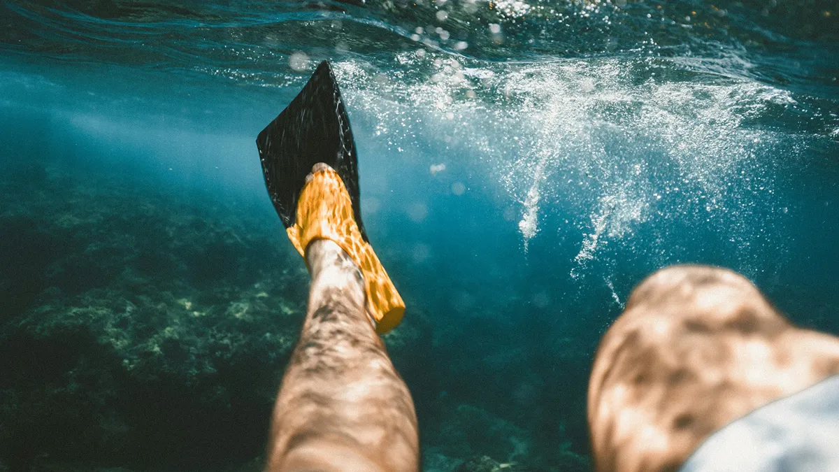 First person view of a swimmer wearing fins underwater