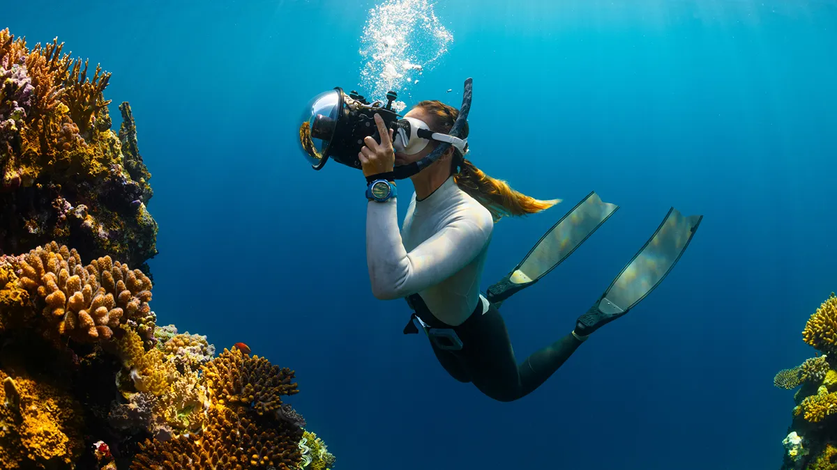 Underwater photographer taking photos of colorful coral reef with professional camera